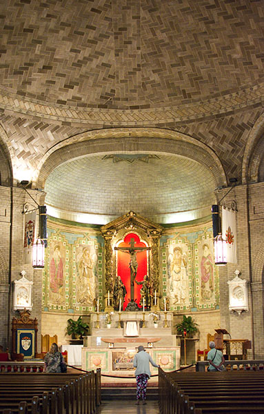 Red altar of St. Lawrence Basilica with lady paying reverence to the crucified Christ