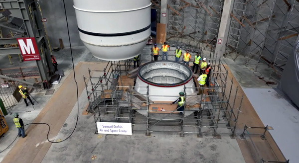 The first of two solid rocket motors that will form the backbone of Endeavour's completed space shuttle stack is about to be placed atop its aft skirt inside the Samuel Oschin Air and Space Center's construction site in Los Angeles...on November 7, 2023.