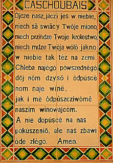 The Lord's Prayer in Kashubian, in black text on a tan background, with yellow, green, and red geometric designs in the margins.