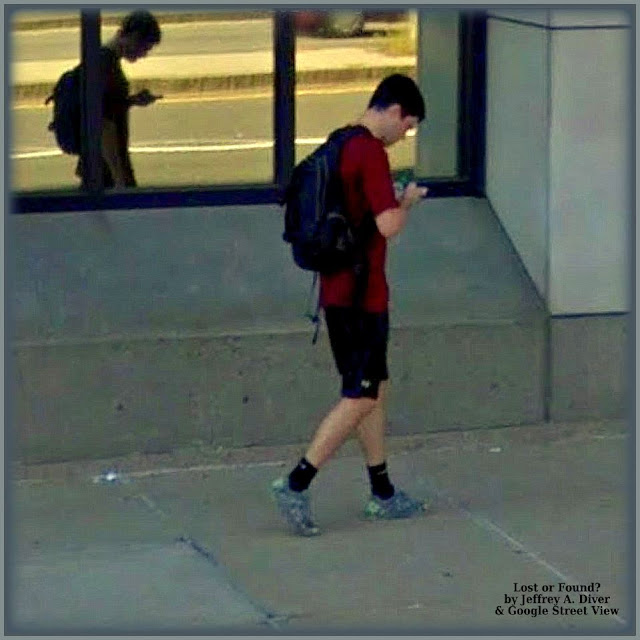 Man in red shirt, shorts, dark socks & sneakers on phone