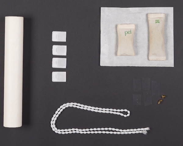 Collection of white objects including bead-like string, white scroll, white pouch and other small white squares on a black background