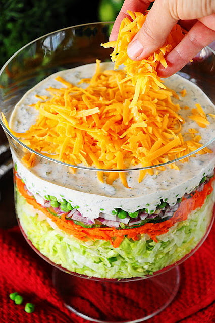 Sprinkling Shredded Cheese on Top of Make-Ahead Layered Salad Image