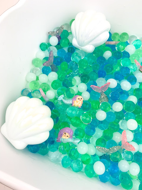 white bin with water beads, shells and mermaids.