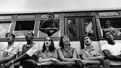 young people join hands in front of bust with others in bus indows during "Freedom Summer" in 1964