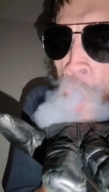 Aviator shades cover Stony eyes of OregonLeatherboy as he exhales smoke onto black leather glove