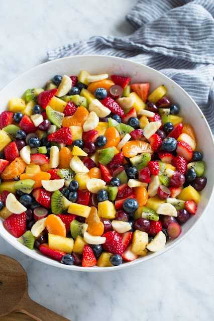 Fruit Salad in a large bowl filled with apple slices, strawberries, melons, and kiwi slices