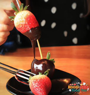 Image of dipping strawberries into melted chocolate.