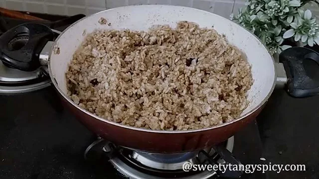 "A close-up shot of hands gently tossing Puliyogare, ensuring that every grain of rice is lovingly coated with the vibrant and tangy flavors of the spice mix."