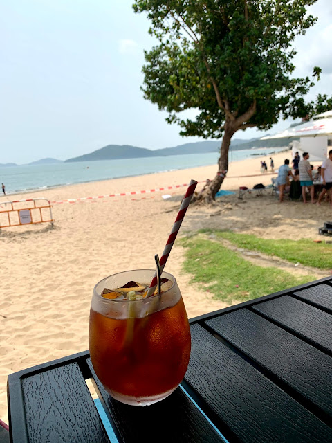 Glass of iced lemon tea on a table with the beach in the background