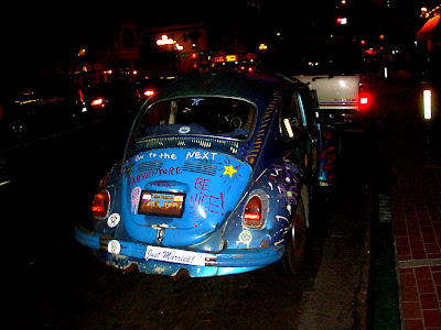 This a picture of blue classic Volkswagen Beetle.  Painted on the Beetle is the quote Be Nice and bumper sticker with a quote Just Married.