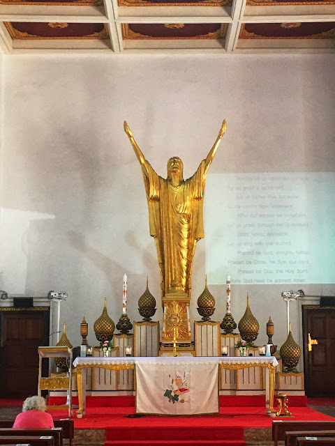 a statue of Jesus in a posture of praise stands at the altar rather than a somber crucifix