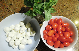 Pictue of the ingredients for a caprese salad - tomatoes, mozzarella cheese, and basil