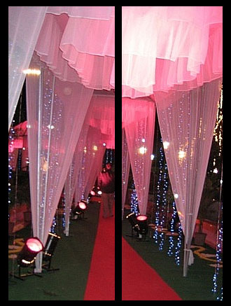 Pink sheer fabric is gathered in tented columns and illuminated with spot