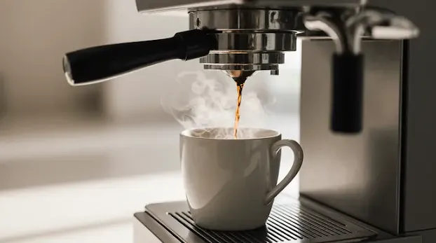 Fresh black coffee pouring from espresso machine into cup – healthy coffee, antioxidants, fat burning boost.