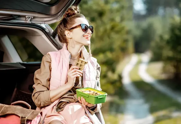 A girl enjoying  road trip snacks
