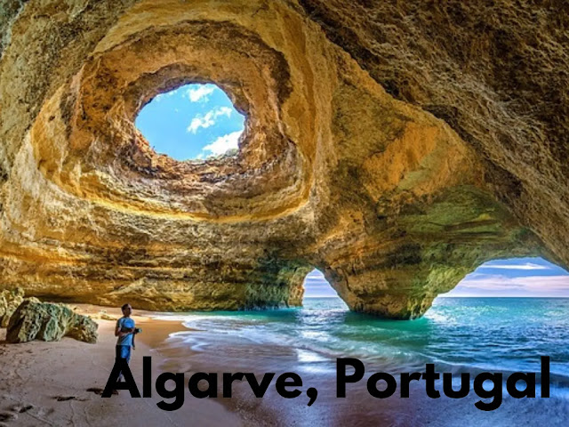 a person standing on a beach with a hole in the rock