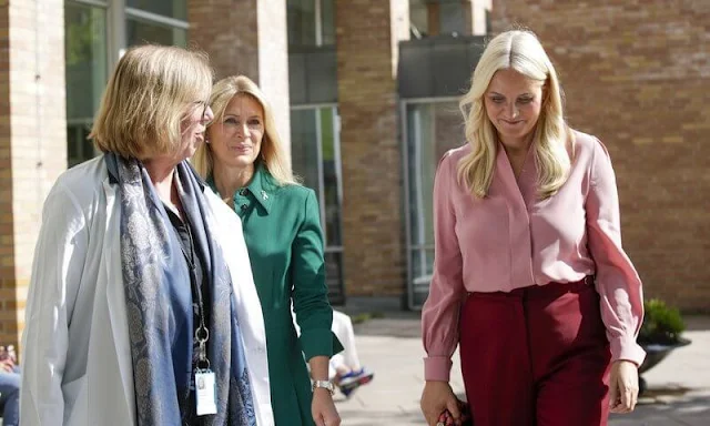 Crown Princess Mette-Marit wore Vesta flared wool-blend trousers by Gabriela Hearst, and pink silk blouse. Maria La Rosa pink clutch