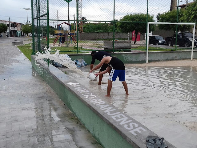 Moradores retiram água com baldes para poderem ultilizar o campo da praça Chaves Neto em Granja-CE