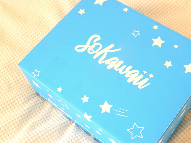 A photo showing a light blue box sitting on a cream blanket, the word 'so kawaii' is printed across the top