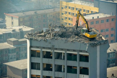 Excavator on the roof of a 12 story building to demolish Excavadora en la azotea de un edificio de 12 pisos para demolerlo