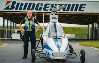 Police woman pilot standing next to a Pegasus E flying car.