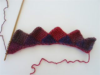 Rainbow colored yarn is worked in rows of triangles and diamonds to form the shawl