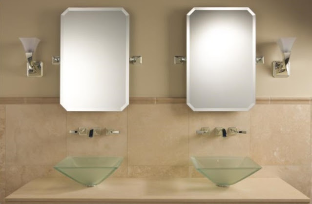 Beige bathroom with glass vessel sinks and sconces on either side of the mirror.