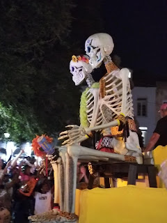 Two large skeleton models are seen seated on a parade float as it travels along a New Orleans street during a 'Krew of Boo' parade.