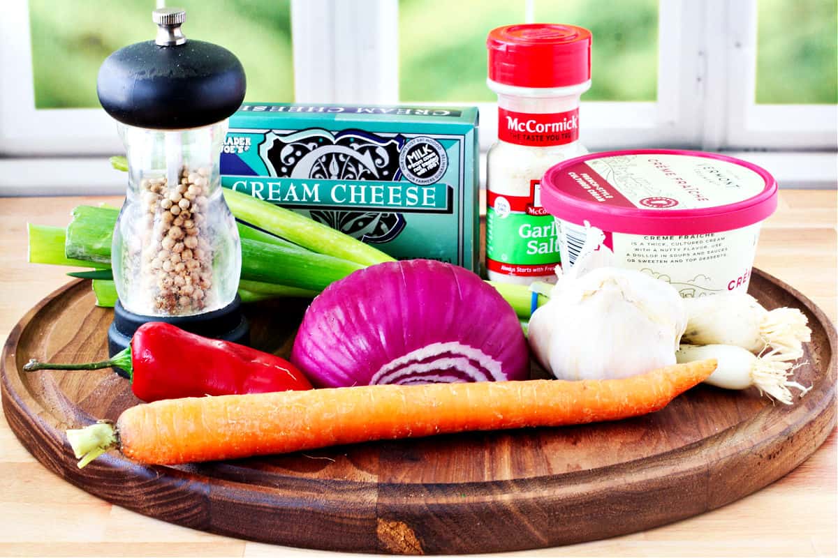 Garlic and Vegetable Cheese Spread Ingredients on a round cutting board.