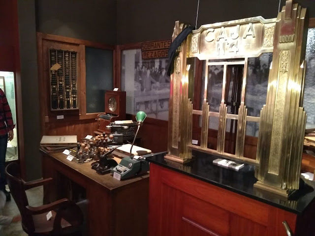 la imagen muestra una ventanilla, máquinas de escribir.. una oficina antigüa