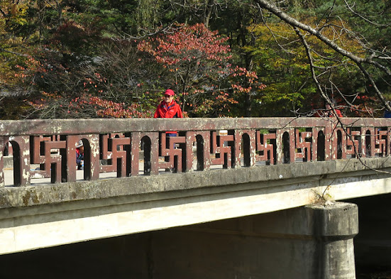 Person walking over a bridge with swastika patterns in the railing.