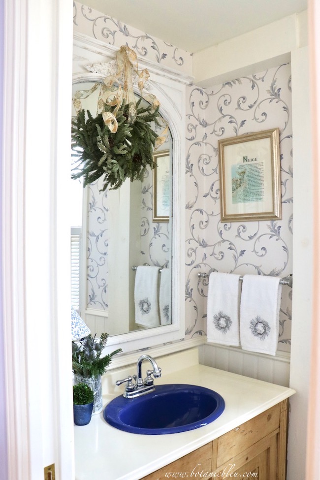 A gold framed NEIGE print and Christmas towels bring Christmas to a French Country guest bathroom.