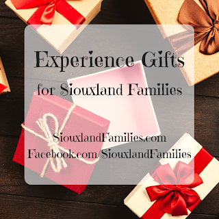 red and white packages tied with ribbons surround an open, empty gift box in the background. In the foreground, the words "Experience Gifts for Siouxland Families"