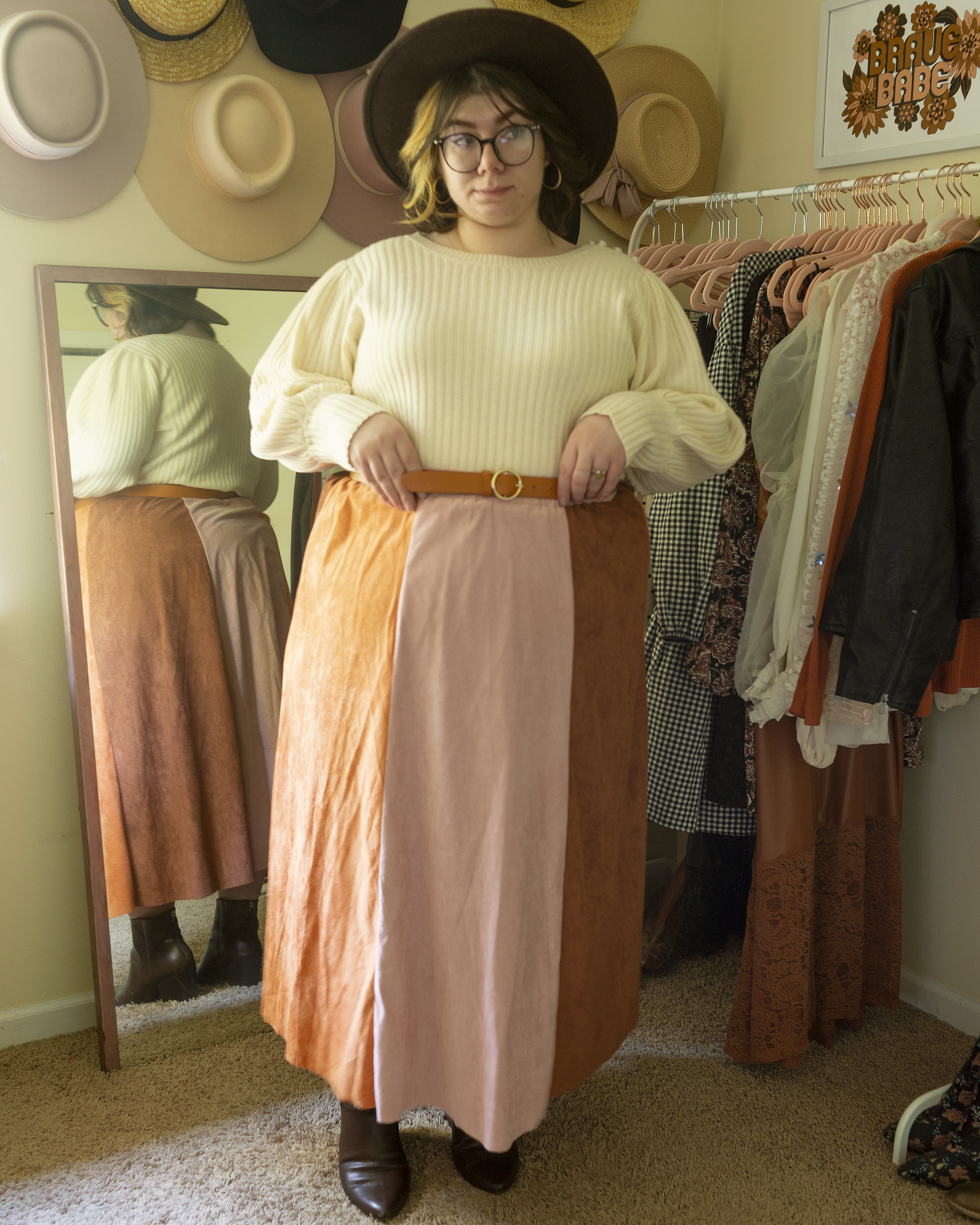 An outfit consisting of cream 3/4 bishop sleeve sweater tucked into a cognac brown, pastel pink and burnt orange paneled maxi skirt and walnut brown boots.