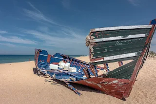 on old wrecked fishing boat washed up on the shores of andalucía