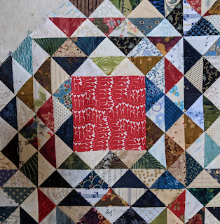 One scrap quilt block with a large red and white print square in the center.