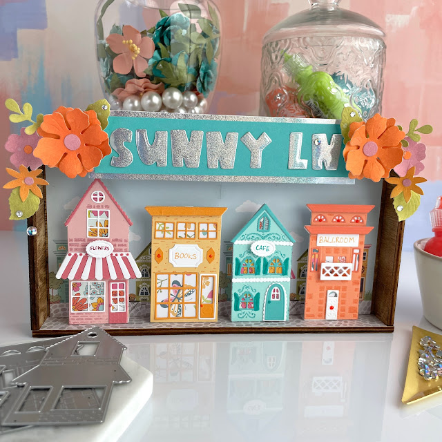 Sunny Lane Vignette created with: Scrapbook.com sunny lane houses, florals and paper, smooth cardstock, holographic paper, pops of color; Tim Holtz distress oxide; Pinkfresh clear drops iridescent