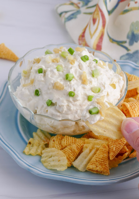 dip on a chip next to a clear bowl.