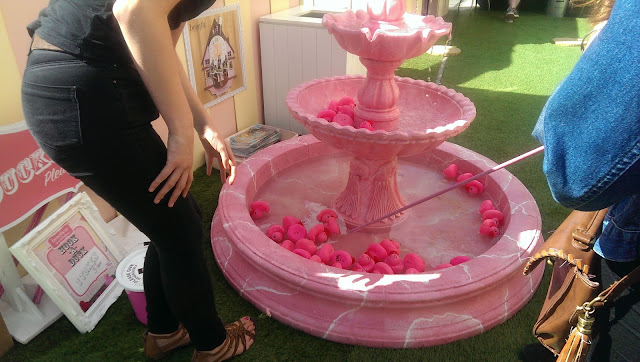A pink fountain with plastic ducks in