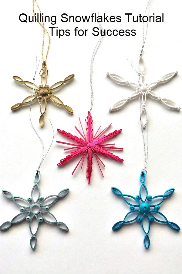 five quilled snowflake ornaments made with brightly colored metallic edge quilling strips