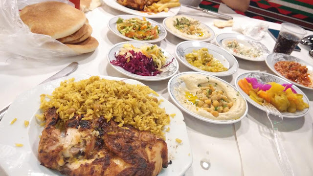 A meal of grilled chicken with bread and various side dishes in Jericho