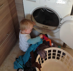 Baby sat on floor emptying tumble dryer