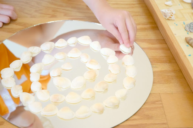 Shells And Mirrors On The Discovery Table. Independedent activity to encourage quiet exploration and loose parts play with natural materials. Fun for a beach or ocean theme for preschoolers or kindergarten, incorporating math, science, and art!