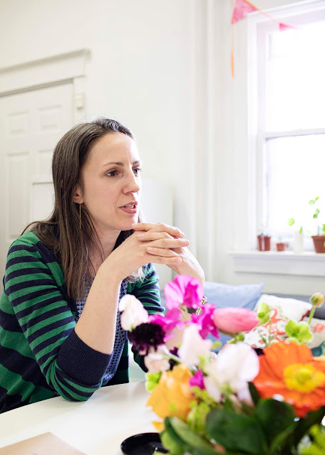 woman sat at table with brightly coloured flowers in front of her