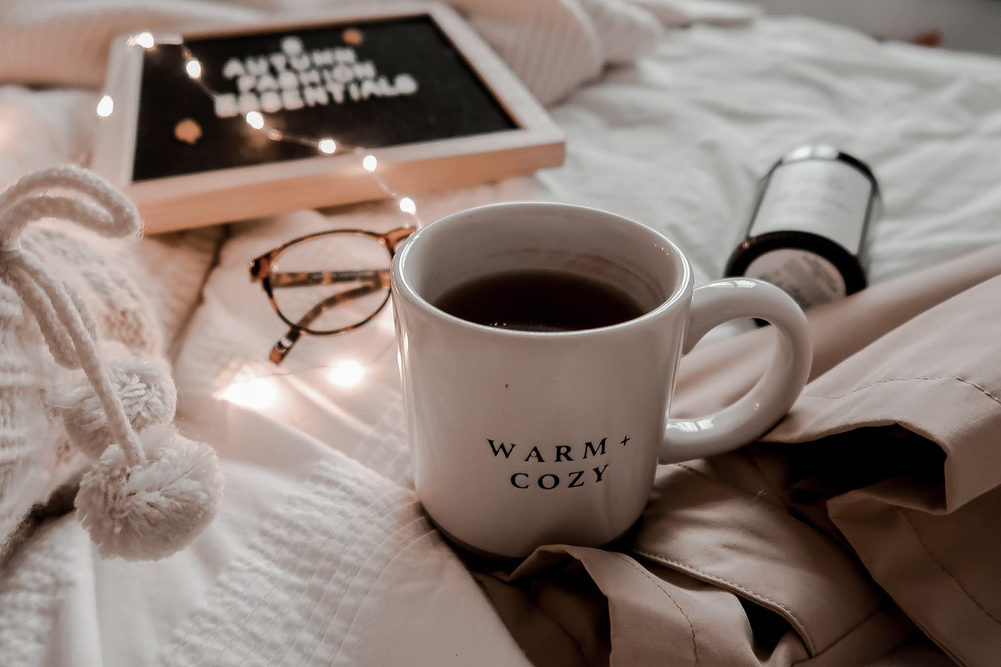 A taupe mug with 'Warm and Cozy' written on it.