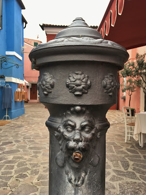 Lion head decorated water fountain on island of Burano, Italy