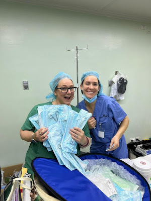 Two nurses in scrubs holding sterilized, packaged surgical instruments — and smiling!