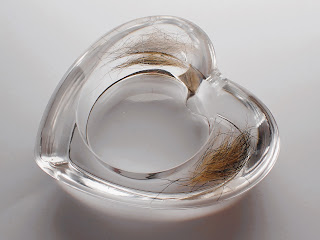 A clear resin heart shaped trinket dish containing pet fur