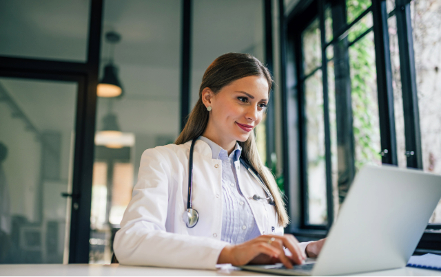 Primary care doctor working at desk looking at the New York 1115 Medicaid Waiver information.