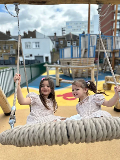 Children on a bucket swing in a playground next to Southend Library at the Forum